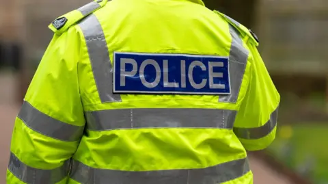 Stock image of a police officer in hi-vis uniform walking away from camera