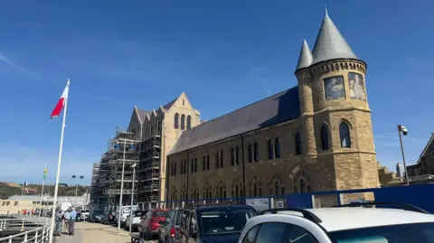 A general view of Old College, a tall brick building overlooking a bay.