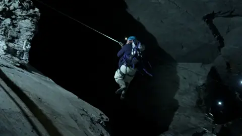 Reporter George Herd zips across a steep drop to reach another patch down the mine