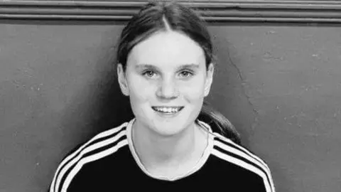 Black and white picture of Holly with long dark hair smiling at the camera