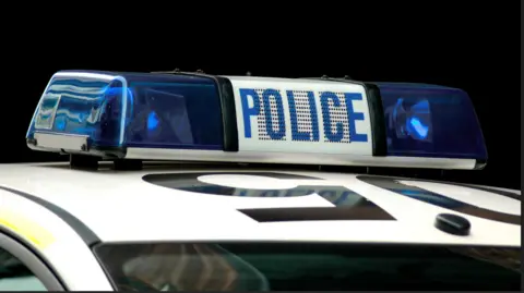 The roof of a white police patrol car, with the blue lights on top of it.