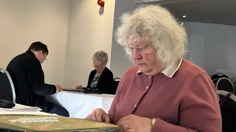 Helen wearing a peach pink cardigan playing scrabble in the tournament 