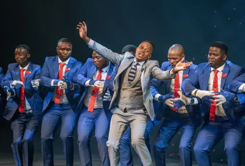 RAJESH JANTILAL / AFP / GETTY IMAGES Men dressed in matching suits dance and sing in unison.