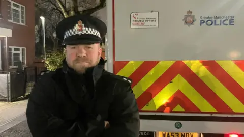 Photograph of Inspector Dan Pickavance next to a Greater Manchester Police van.