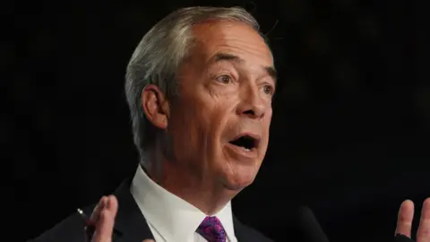 Reform UK leader Nigel Farage speaks in front of a black background while wearing a white shirt, black suit and purple tie.