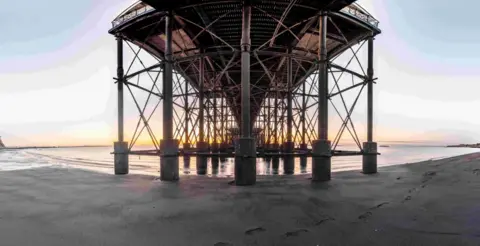 Underneath Penarth pier - the base of the structure surrounded by sand and sea