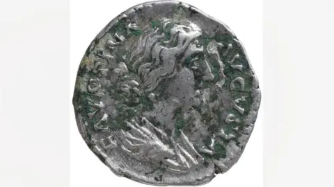 Andrew Williams/Norfolk County Council The front showing the empress Faustina. She is in profile, with hair pulled into a bun at her neck. The coin shows signs of greening. It dates to AD161-75.