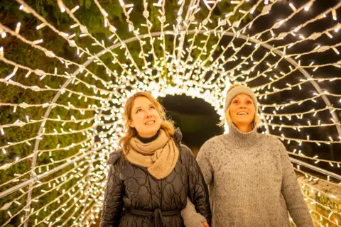 Phil Wilkinson Two woman look up at a tunnel of lights as they walk through it