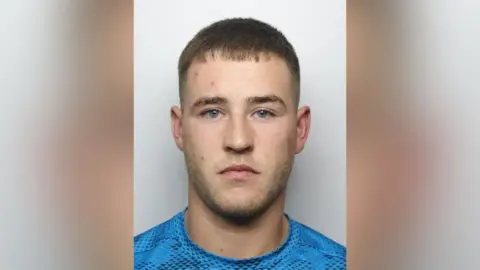 South Yorkshire Police A mugshot of Regan Urruty Dever, looking straight at the camera and wearing a blue top