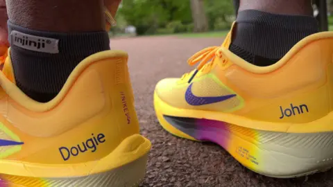 A close up of yellow trainers with the names Dougie and John on the heels