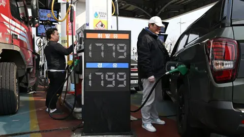 Getty Images People fill up their cars at a petrol station in Seoul 