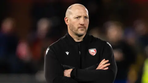 George Skivington stands with his arms folded across his chest