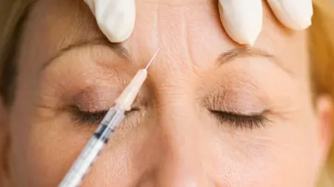 Needle put on woman's face with gloved hands on the top