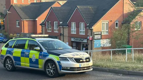 A police car in front of a Costcutter shop