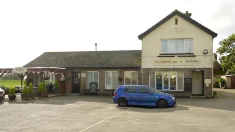 The Union Inn in Jersey with a blue VW car parked outside it in a parking space.