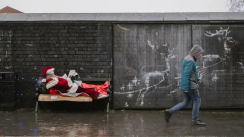 Jack Spicer Adams Banksy artwork shows the Santa sculpture laying on a bench being "pulled" by two reindeer