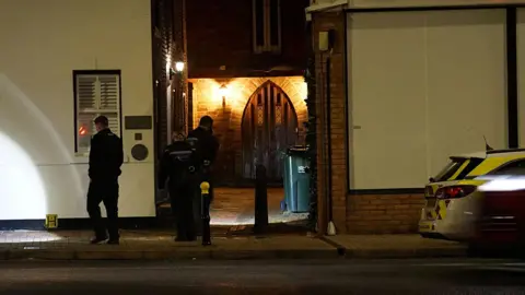 Two police officers with torches carry out a search of the area in the dark