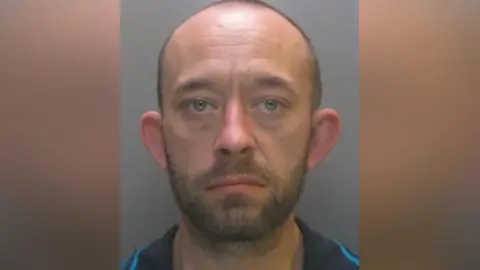 Mugshot of Martin Jackson. He is bald with faint dark hair and black beard.