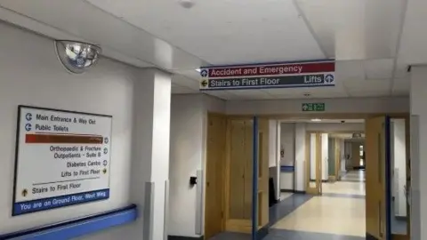 Hospital corridor with a sign for A&E.