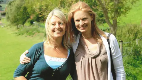 Hetti Barkworth-Nanton Hetti (right) is pictured with her arm around her best friend Joanna (left). They are standing in a green field. There are trees behind them and it is a sunny day.