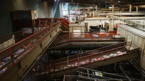 Getty Images Mixed material waste for recycling moves along conveyors at the Veolia Southwark Integrated Waste Management Facility in London. There is a range of different coloured materials on the conveyor belts