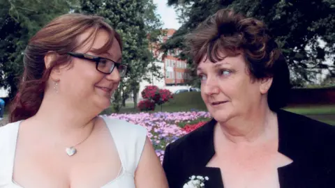 Family photograph  June Fox-Roberts with girl  Abi Sheppard connected  her wedding day, pictured successful  beforehand   of a tract   with flowerbeds