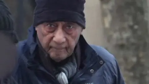 BBC Malcolm Phillips head and shoulders image wearing a coat and hat while arriving at court in a grab from footage