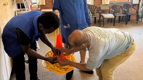 Mayeni Jones / BBC People work on a bird scaring device