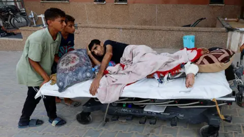 An injured Palestinian man is pushed on a hospital bed into Nasser hospital in Khan Younis, in the southern Gaza Strip, after being evacuated from the European Gaza hospital (2 July 2024). PHOTO/Reuters