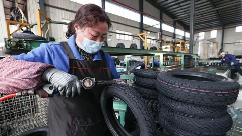 A woman processes tyre orders at a vehicle factory in China 