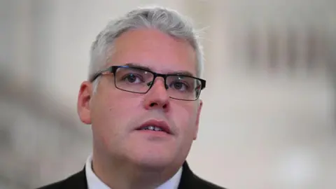 Getty Images A man with short grey hair wears black glasses with clear lenses 