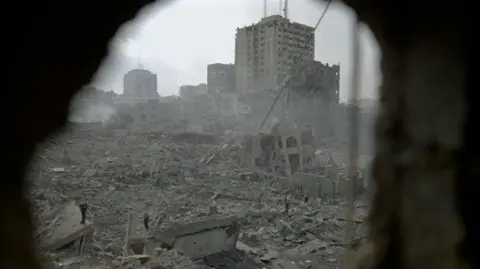 scene of destruction in gaza, with buildings turned to rubble seen through a hole