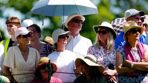 PA Wimbledon spectators trying to keep cool in the shade and under umbrellas