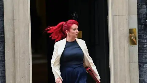 PA Media Louise Haigh appearing extracurricular  the beforehand   of Downing Street - she is walking with a reddish  folder nether  her arm. She has distinctive dyed reddish  hair, and is wearing a pick  blazer and bluish  top. 