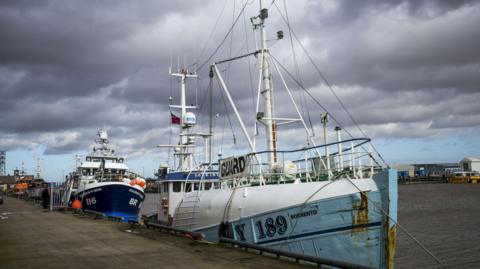 Two trawlers sit dockside in Grimsby
