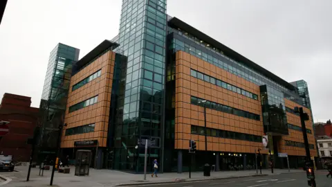 PA Media An exterior view of the Liverpool Civil and Family Court centre, which has salmon coloured cladding and glass panelled stairwells.