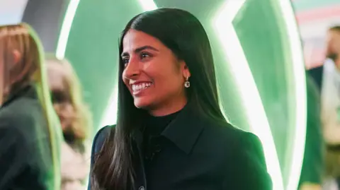 A woman with long dark hair smiles broadly