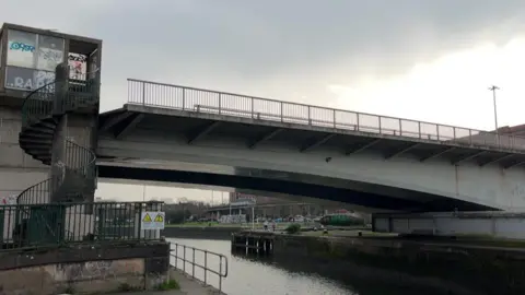 A close image of the Plimsoll Swing Bridge stuck open at a slight angle beside a spiral staircase. 
