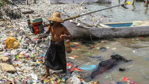 A fisherman arrives at the beach full of rubbish that mostly consists of plastics thrown by local residents and brought by sea currents from various locations in the Kwanyar district, Bangkalan, Madura Island of Indonesia