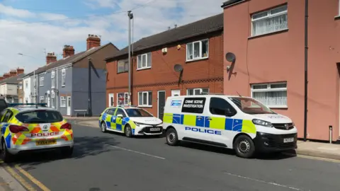 Two police cars and a police van parked in a residential street in Grimsby. 