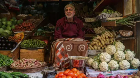 A man sells vegetables in a shop at a market in Srinagar, Jammu and Kashmir, on February 28, 2025, ahead of the Muslim holy fasting month of Ramadan. 