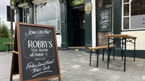 Holly Nichols/BBC The outside of a pub with a board outside which says Robby's Tea Room