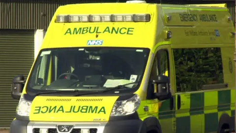 A East Midlands Ambulance Service van in bright yellow and green. The van is stationary with no one in it.