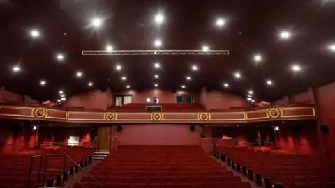 Durham County Council Inside the Empire's auditorium which has red seats and red walls. There is a balcony with additional seating.