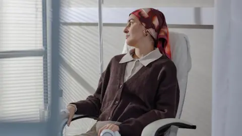 A woman sitting on a chair looking out a window