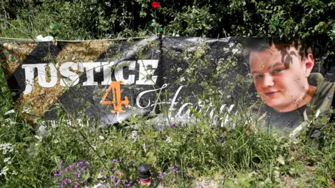 Reuters Banner on theroad outside RAF Croughton showing an image of harry Dunn and the title- Justice 4 Harry
