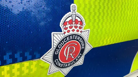 The Gloucestershire Police emblem on a high-visibility police car