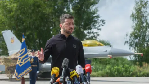 Getty Images President Zelensky at a ceremony at a secret location, flanked by the jets