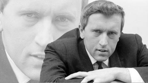 David Frost leans forward with one arm over the other.