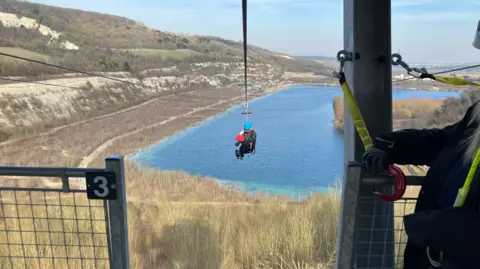 Leanne Rinne/BBC Lord Mackinlay of Richborough on the zip wire above a lake